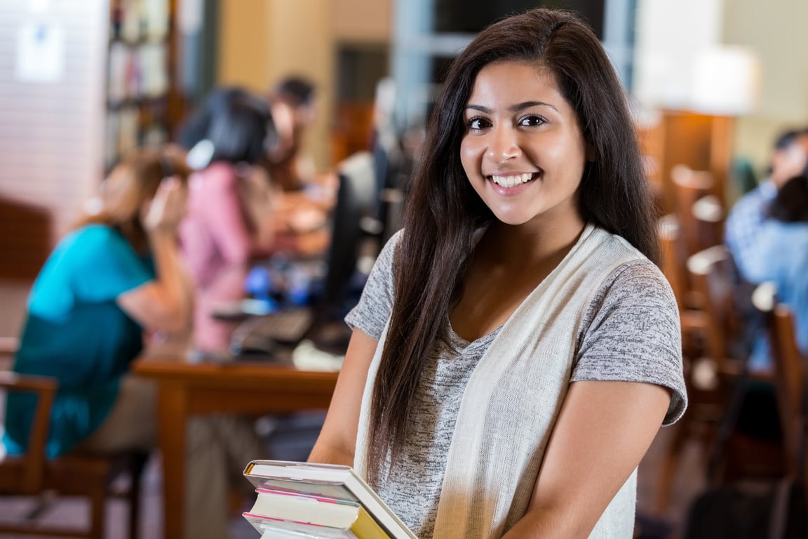 Pretty Indian teenage high school student in library