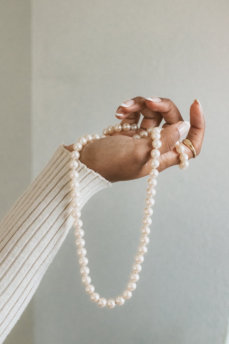 Person Holding a Pearl Necklace 