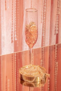 Crystal Glass with Gold Rings and Necklace on the Table