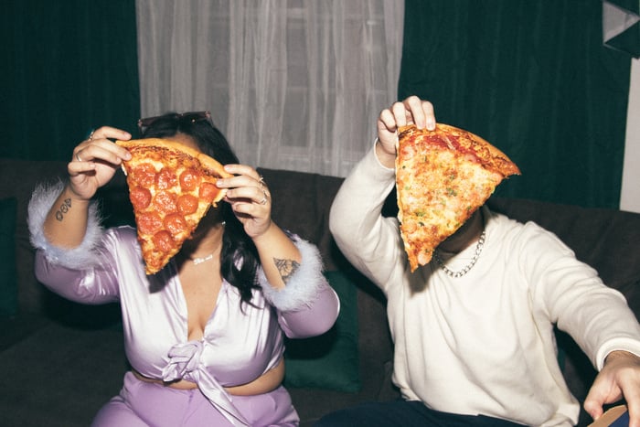 People Holding Up Pizza Slices